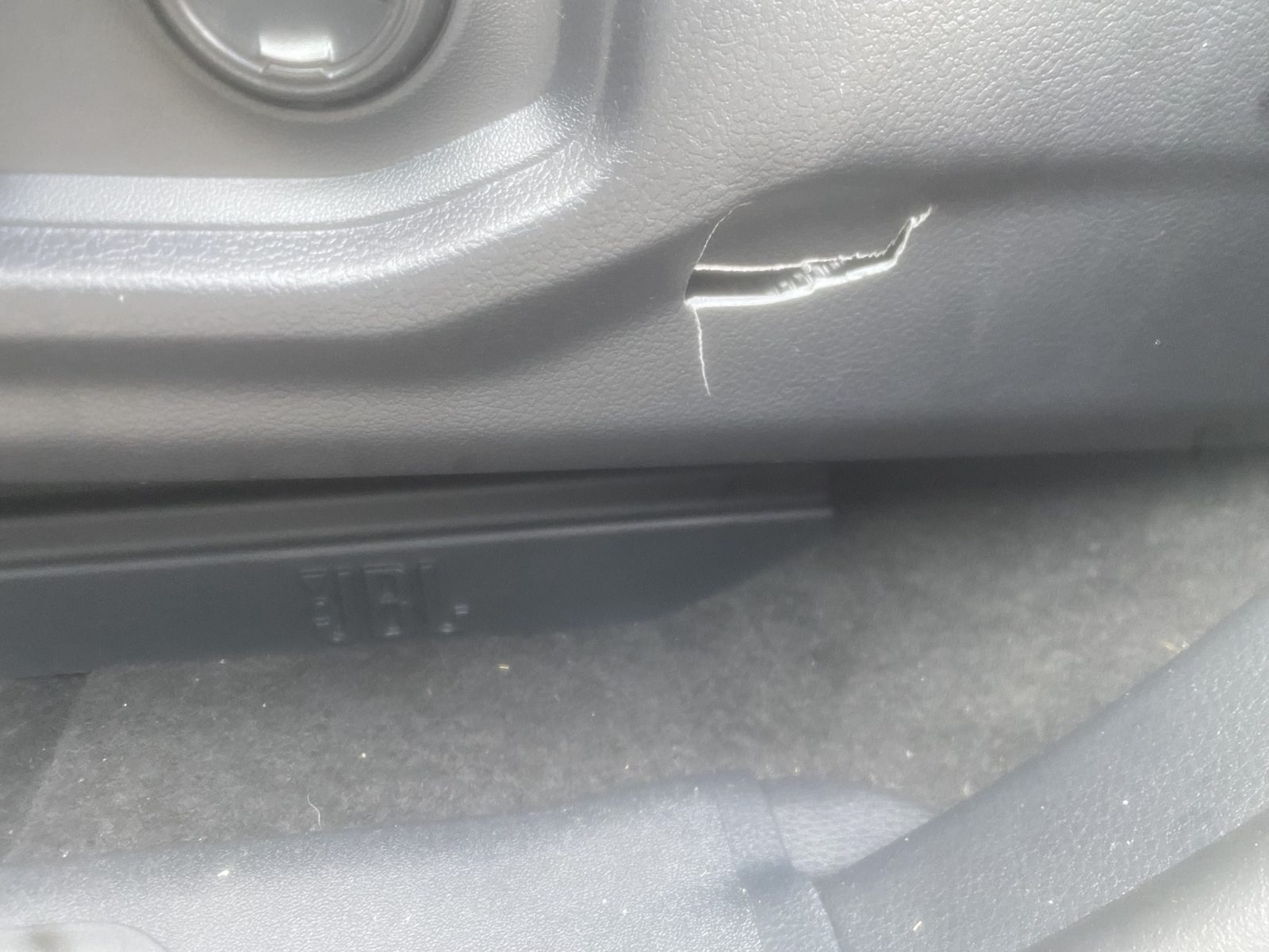 Driver seat side control panel with a crack next to the seat adjustment controls