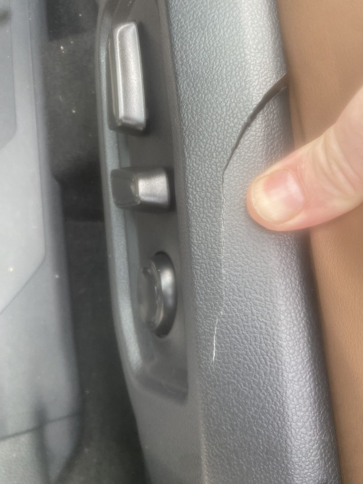 Long crack running down the side of the driver seat control panel beside the seat switches
